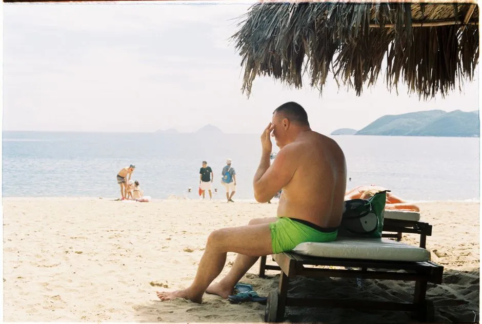 A man on a beach lounger holds his head in his hand